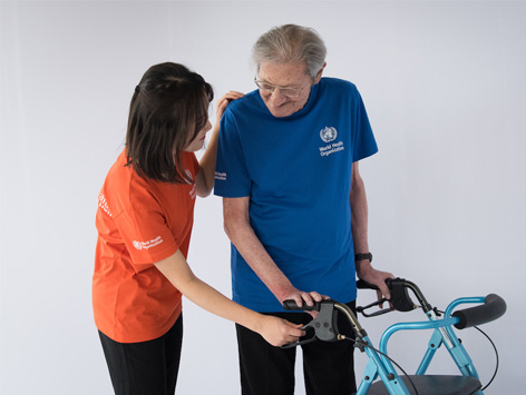 A woman shows a man how to use the brakes on his rollator.