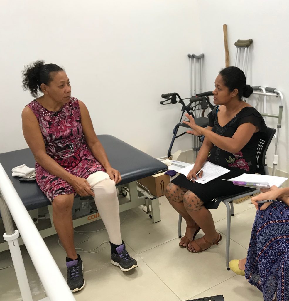 a service provider sitting with a service user who has an artificial limb, carrying out an assessment interview