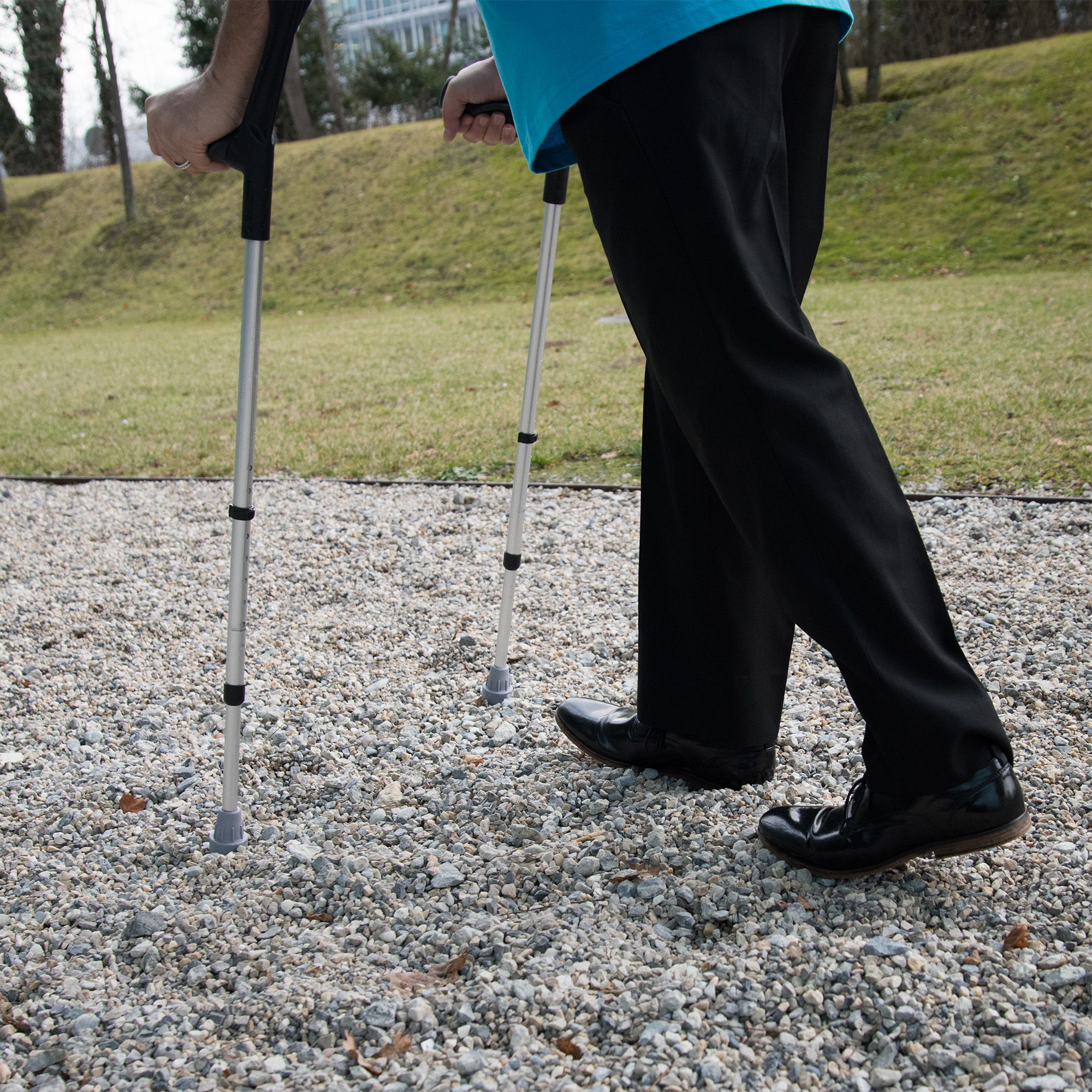 A person using elbow crutches on uneven ground.