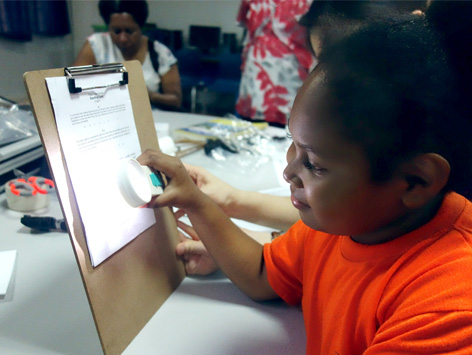 Young girl using a magnifying glass and light to read