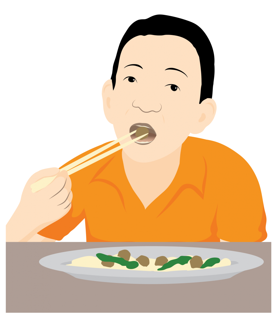 A young boy uses chopsticks to place food in his mouth. A plate of food sits on the table in front of him.