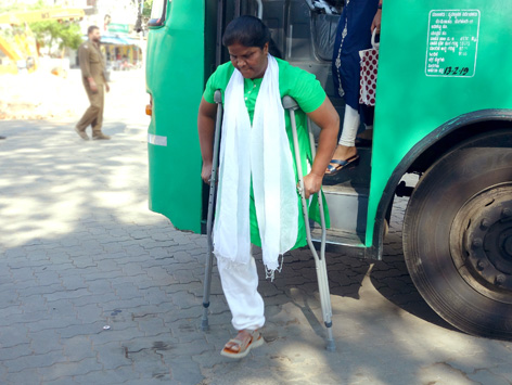 A woman with an above knee amputation uses axilla crutches to get out of a bus.