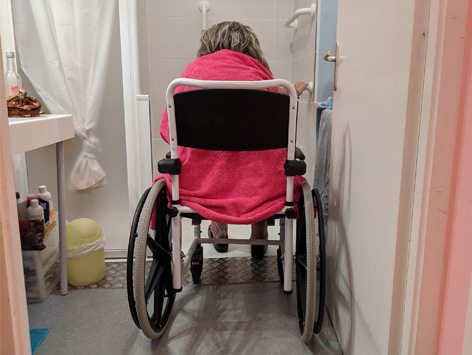 An individual using a shower chair to shower