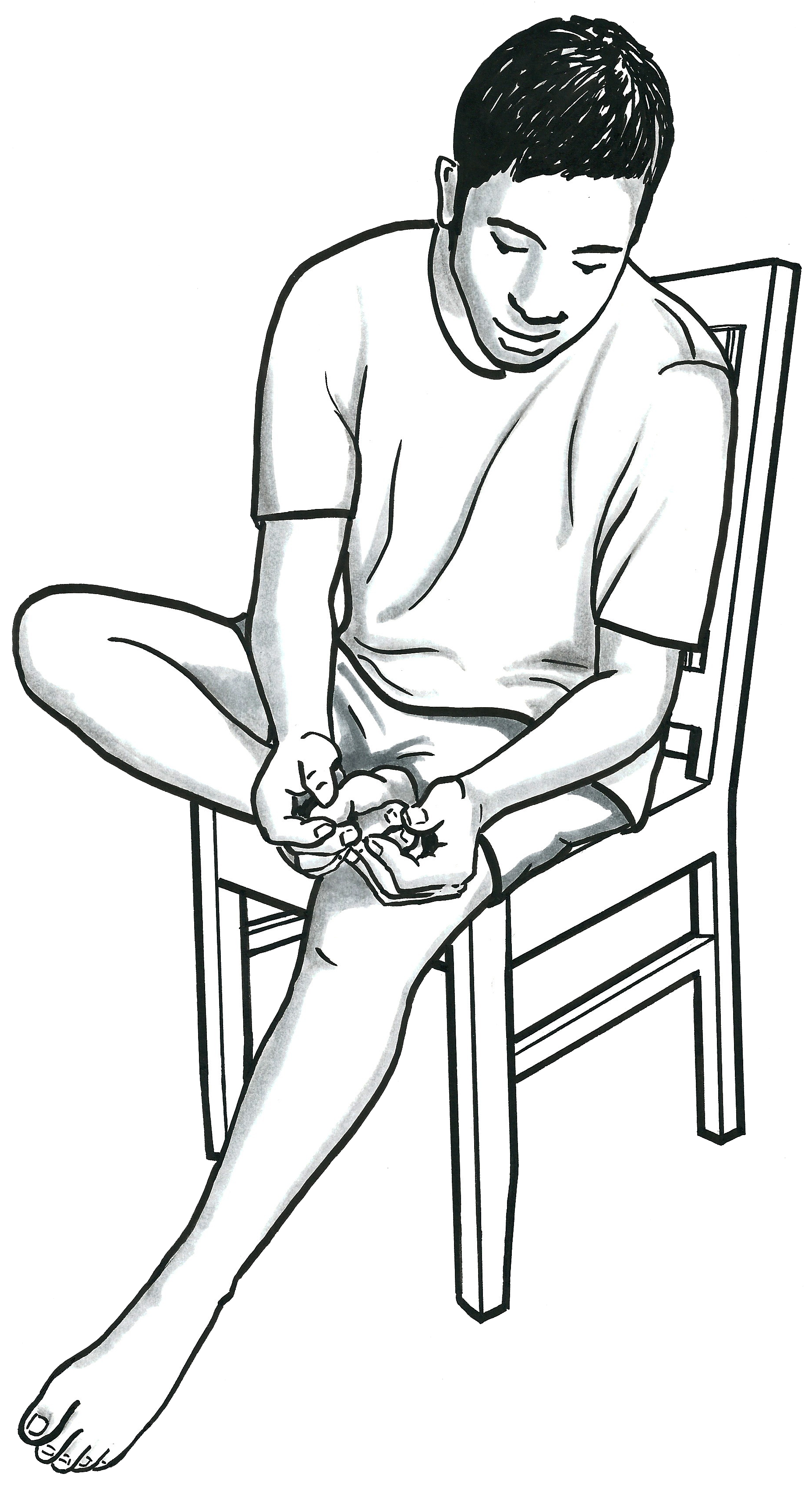 A man sits in a chair, with one leg bent up so he can look closely at the bottom of his foot.