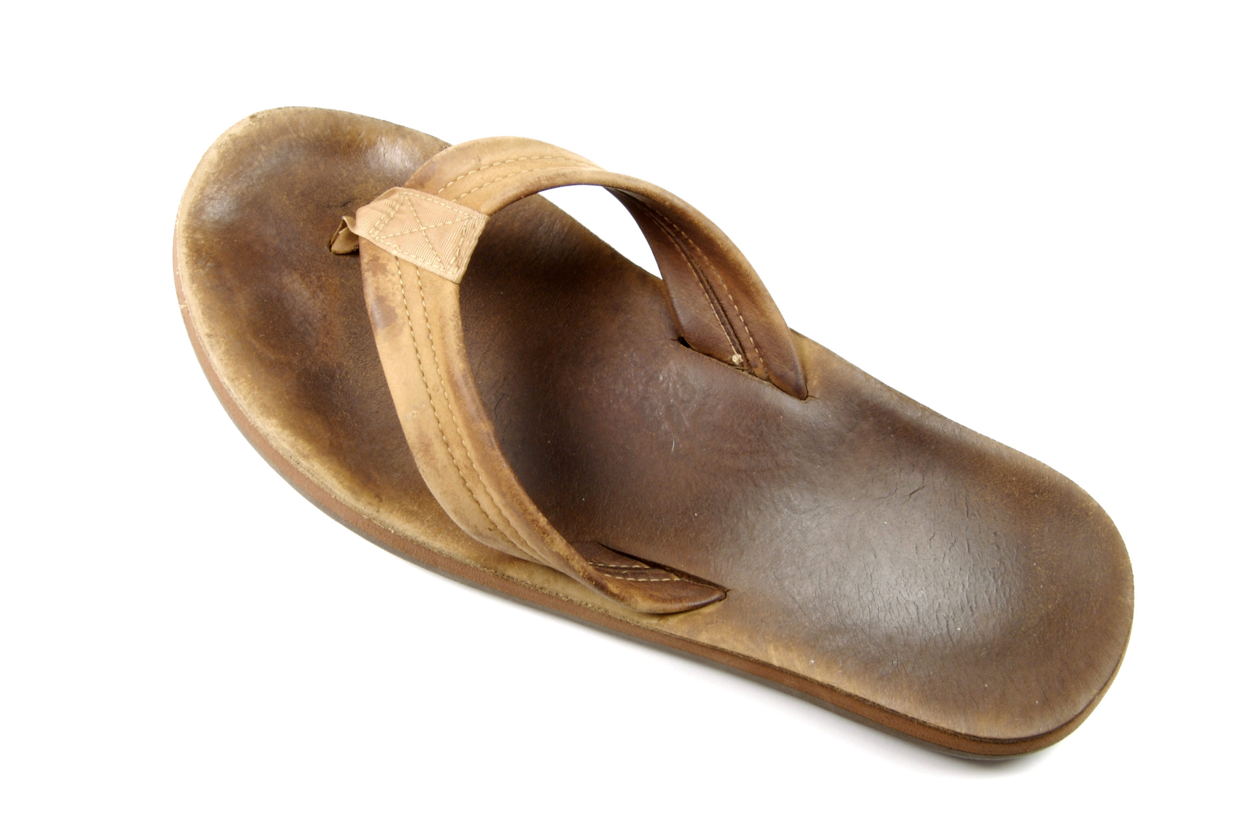 A flat sandal with a thin base and one strap that goes around the front of the foot and can be held between the big and second toe.