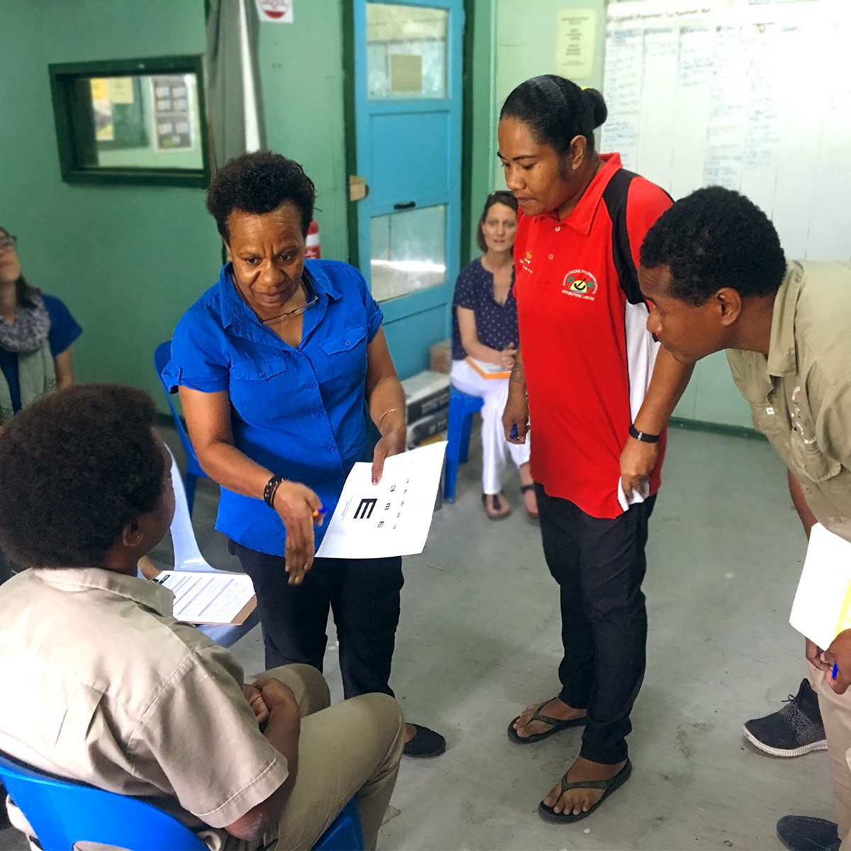 A woman holds an e-chart, explaining it to a group of three people who listen intently.