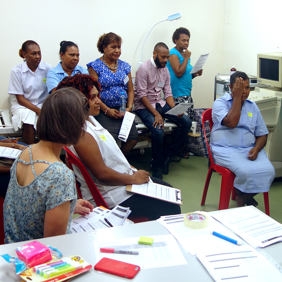 A group of seven people watch another women practice a vision screen.