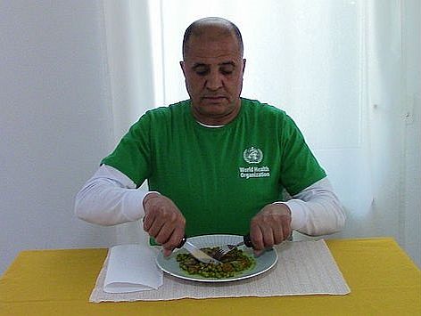 A person sits at a table with a knife and fork to eat