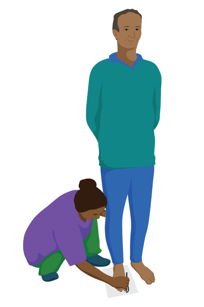 A person stands on a piece of paper while a health worker draws around their foot.