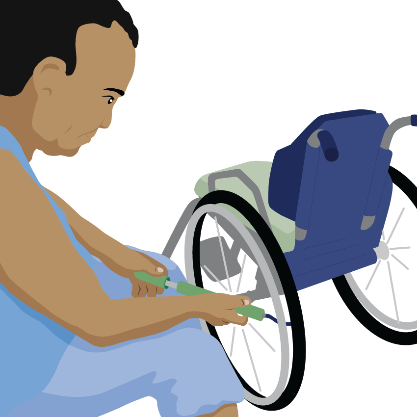 A person sits next to their wheelchair pumping up the tyre.