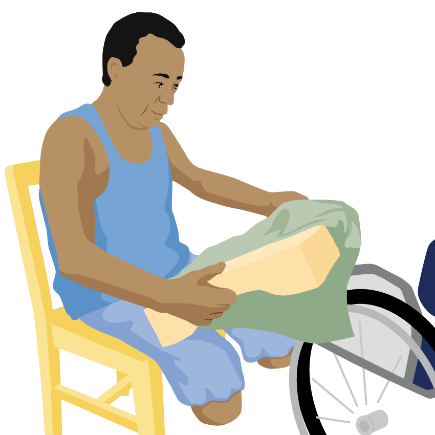 A person sits in a chair and removes the cover from their wheelchair cushion.