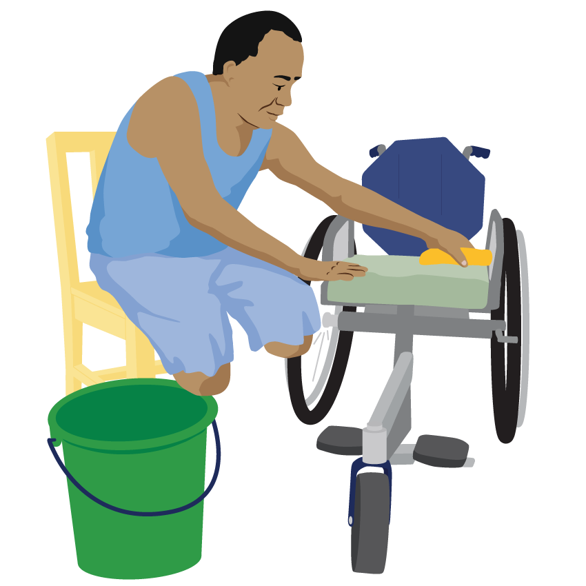 A person sits on a chair next to their wheelchair. They wipe the cushion with a cloth. A bucket of water is close by.