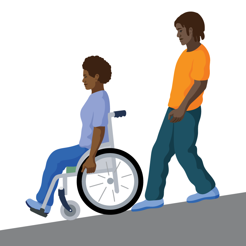 A woman leans backwards with arms straight to hold the push rim at the front. Her assistant follows closely behind.