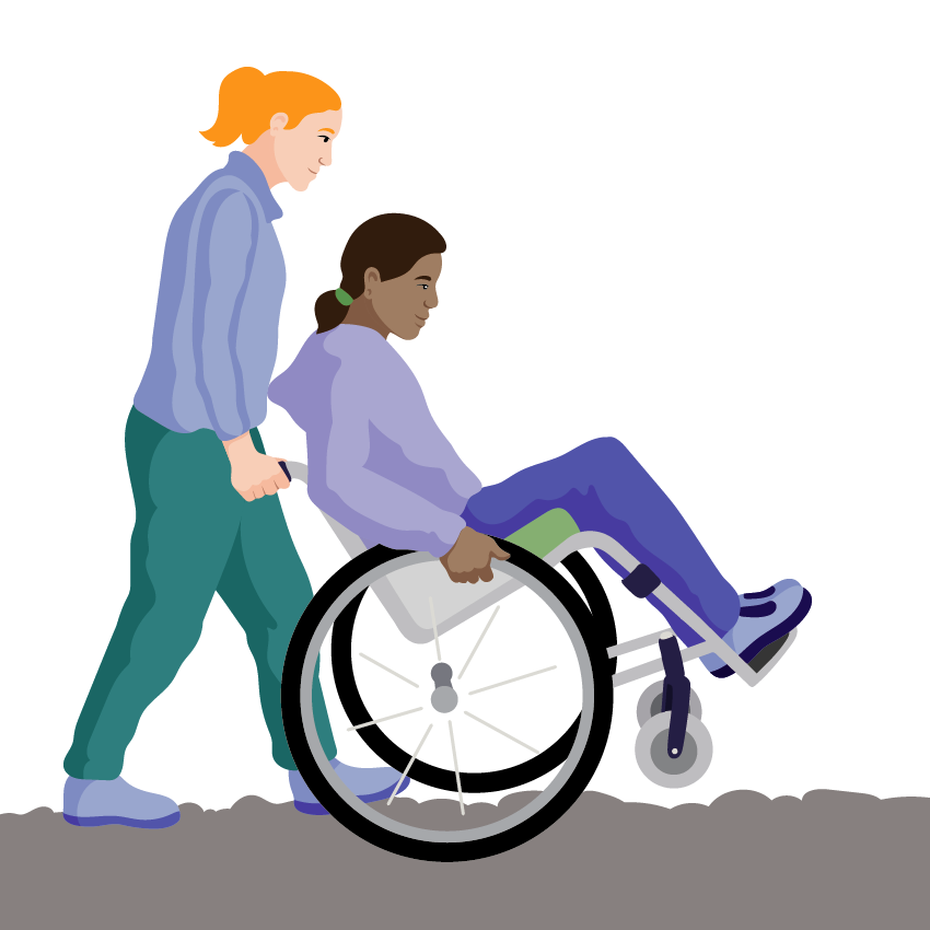 An assistant holds the push handles to balance the person on their rear wheels while moving over rough ground.