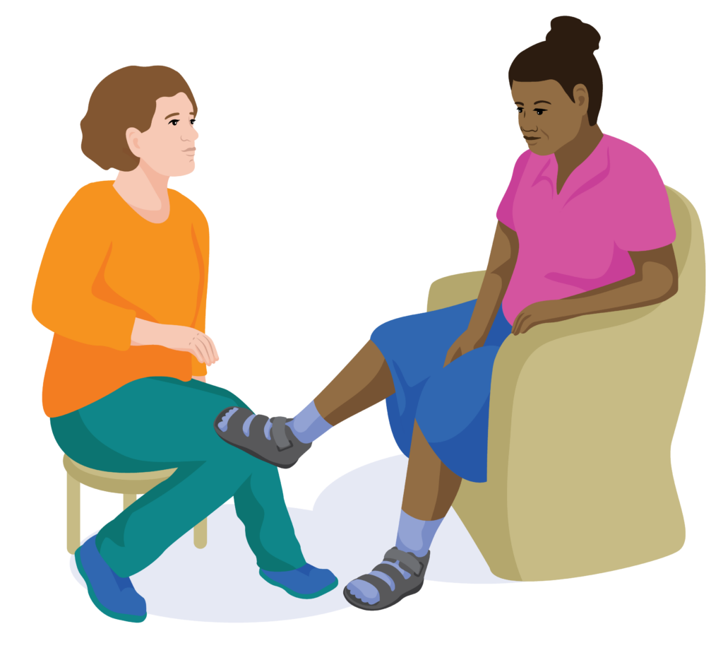 Jospehina props her foot up so a health worker can check her therapeutic footwear.