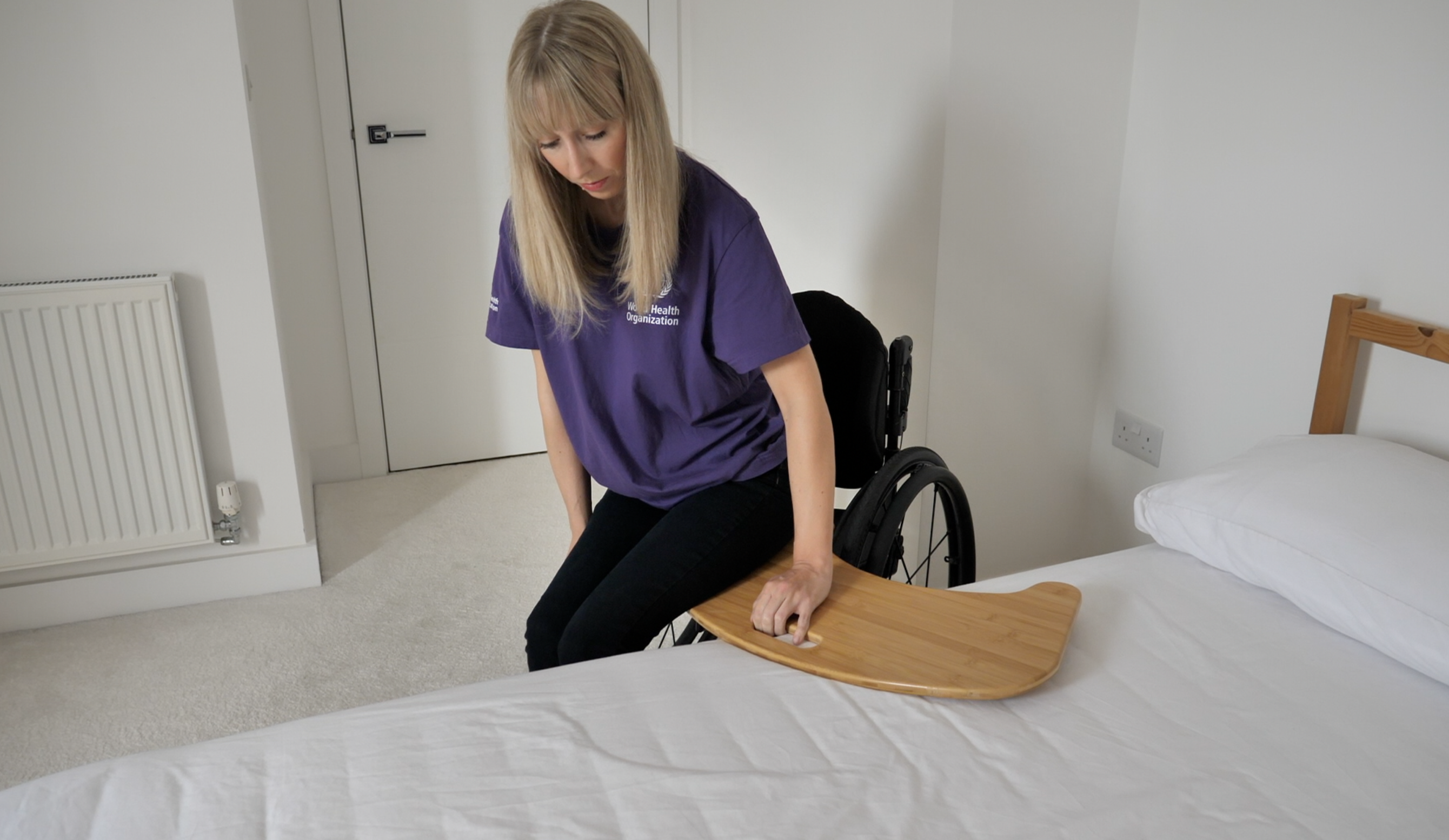 A person leans to the side to position the transfer board under one buttock.