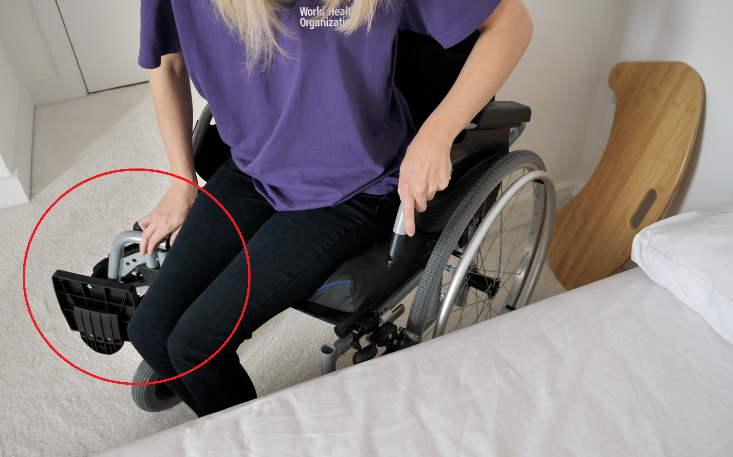 A person preparing to transfer moving the footrest out of the way.