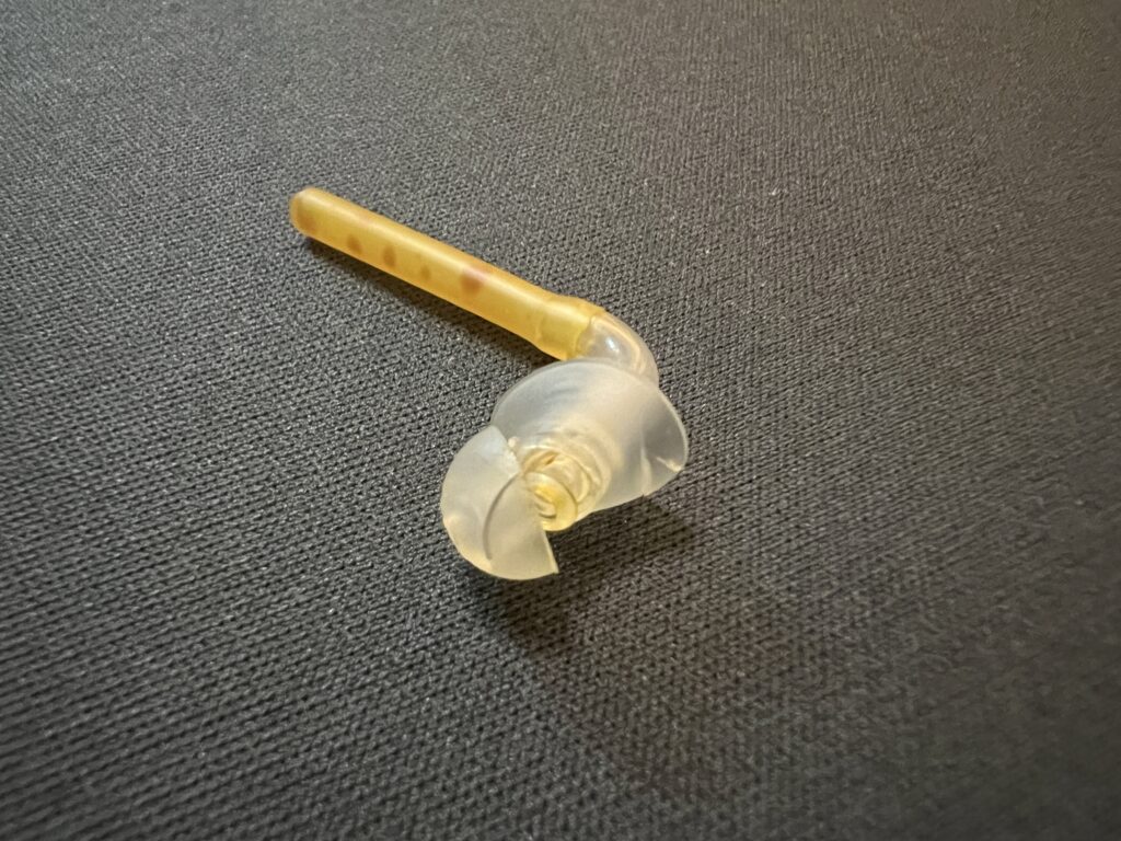 An earmould with a crack across the centre of the earpiece.