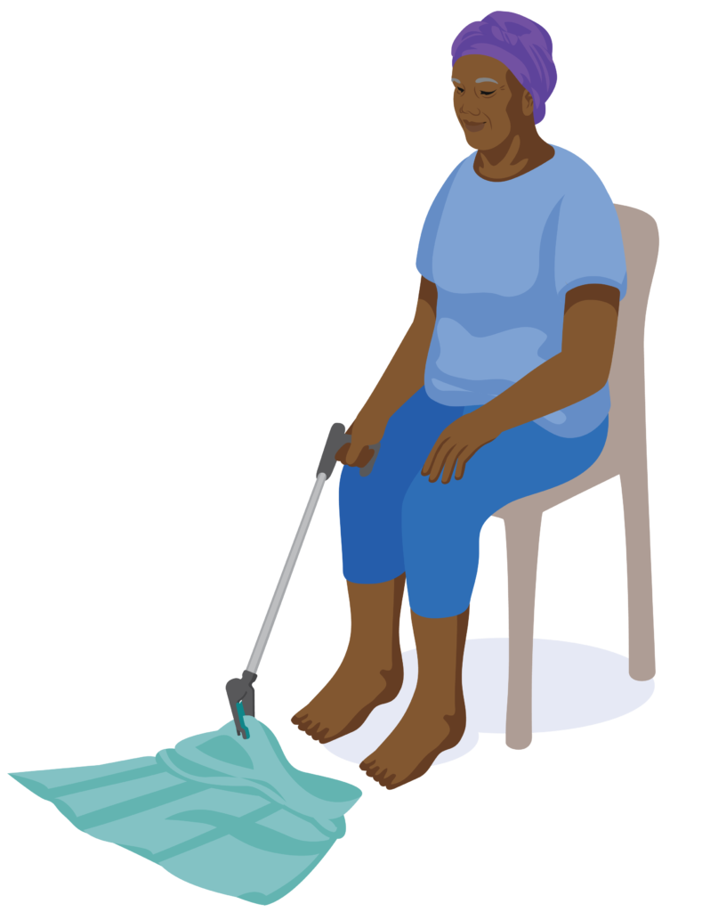 A person is sitting on a chair. They hold a reach and grab tool in their right hand with the trigger handle pressed. The grasping claw grips a skirt which is on the floor.