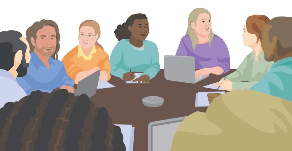 Eva is wearing her hearing aids and sitting with a group of people in conversation around a table. A tabletop microphone transmitter is positioned in the centre of the table with open laptops and notes around the side.